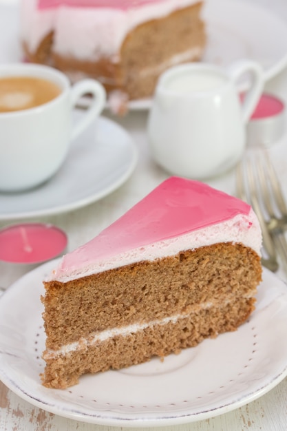 Cake on white plate and cup of coffee on white wood