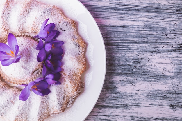 Cake on white plate decorated with crocus flower on wooden bright beautiful . Spring. Top view. copyspace.