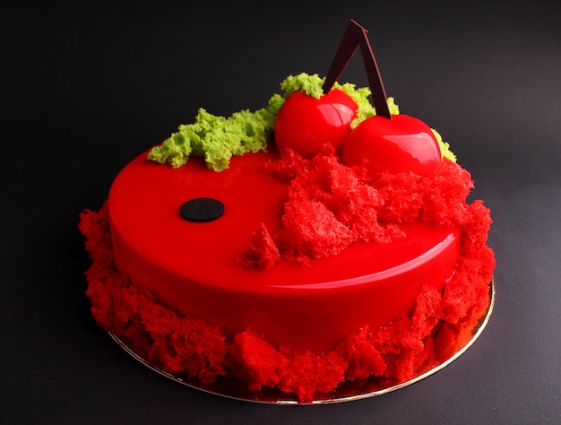 Cake with berry mousse in the mirror red glaze decorated with a molecular biscuit. On the black background.