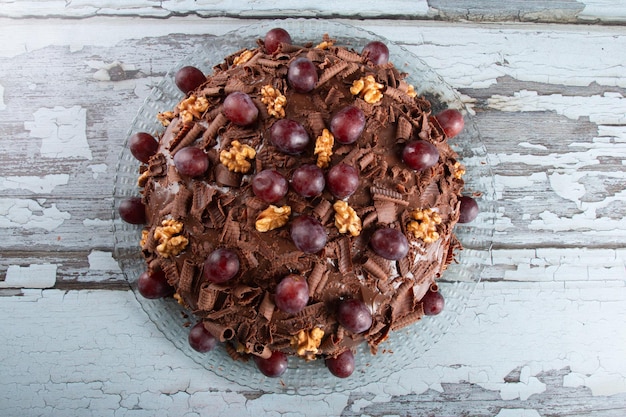 Cake with chocolate icing and grapes on a rustic background