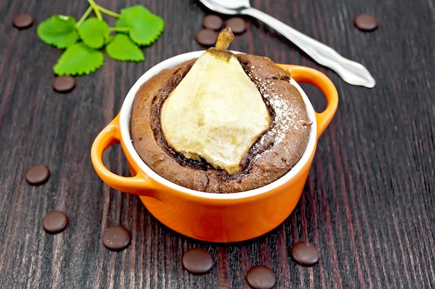 Cake with chocolate and pear in red bowl on board