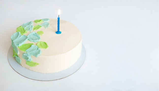 Cake with green and blue abstract decor and one candle. copy space