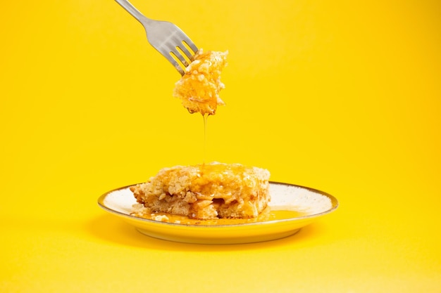 Cake with honey on plate on yellow background