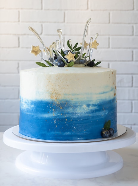 Foto torta con ciotola di isomalto, bacche, foglie e stelle. aggiunta di stelle d'oro. fase 5 decorazione della torta. passaggio 5 di 5.