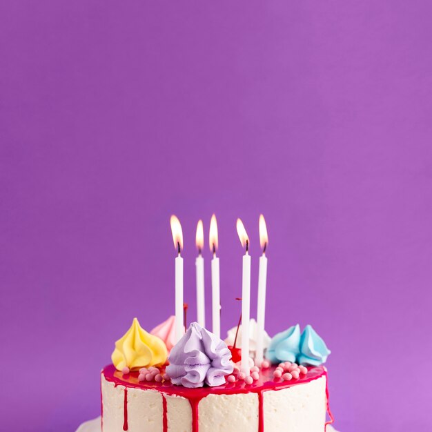 Торт с зажженными свечами на фиолетовом фоне