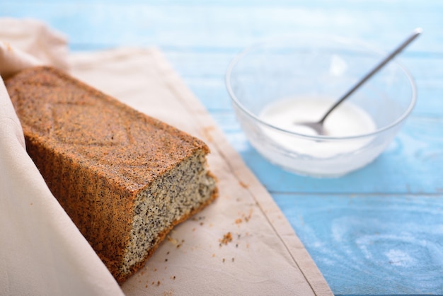 Cake with poppy seeds wrapped in a napkin and glass cup with creamy icing