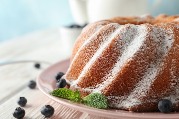 Cake with powder sugar and blueberry on wooden background