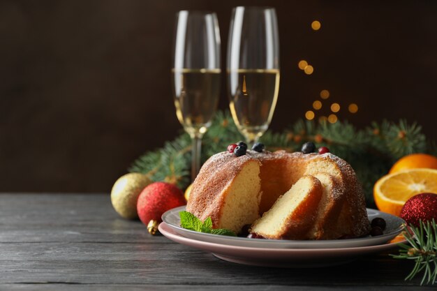 Cake with powdered sugar, berries and mint on wooden background