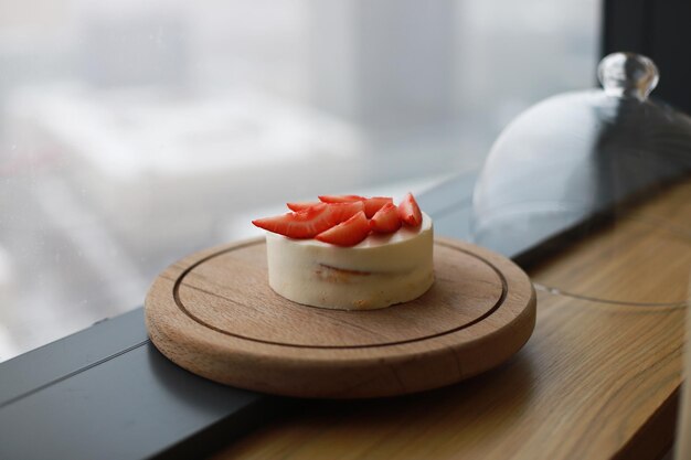 Cake with strawberries on a wooden plate