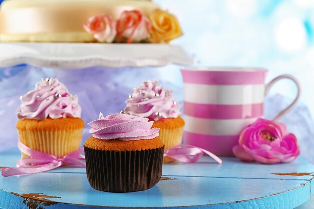 Photo cake with sugar paste flowers and cupcakes on light background