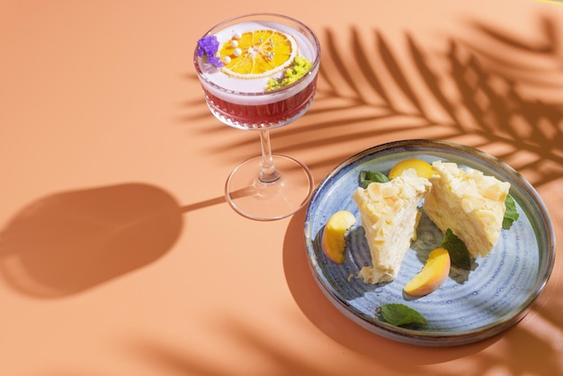 Cake with a summer cocktail on an orange background, space for text on top