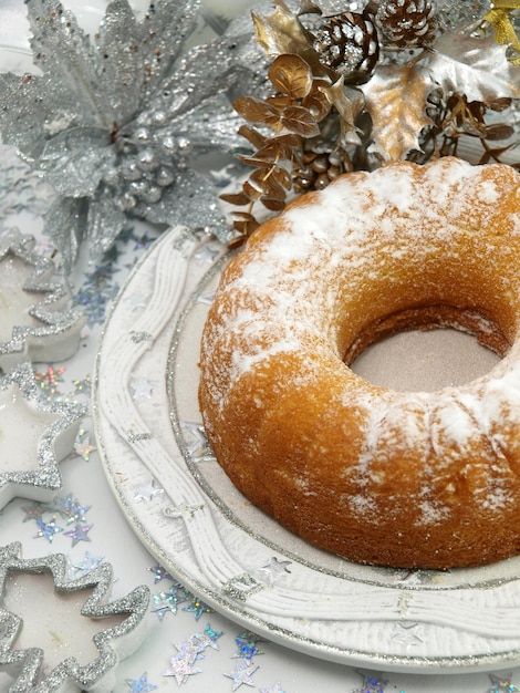 A cake with white sugar on it and a silver decoration on the side.