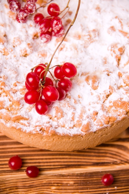 Foto torta su un tavolo di legno decorato con zucchero a velo e bacche rosse