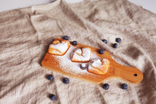 Cakes with blueberries sprinkled with icing sugar on a wooden background Top view Healthy eating Breakfast idea for children and adults