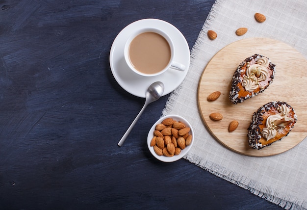 Dolci con gocce di cioccolato e decorazioni crema sul bordo di legno su legno nero.