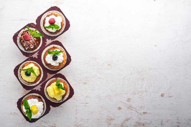 Photo cakes with fresh fruits and cream filling on a wooden background top view free space for text