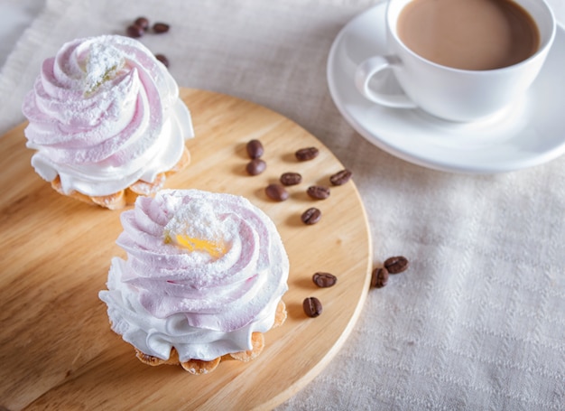 Cakes with whipped egg cream on wooden board.