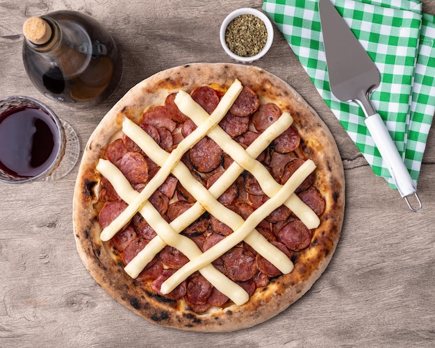 Foto salsiccia calabrese e pizza al formaggio a crema catupiry su tavolo di legno con vino oregano e spatola