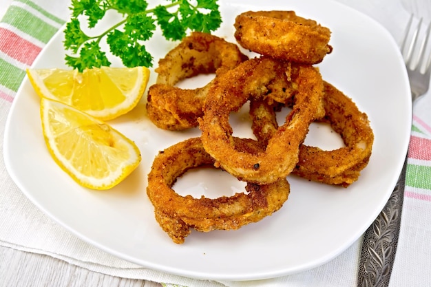 Calamari fried with lemon and fork on plate