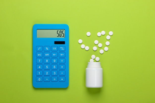 医療費の計算。緑の背景に電卓と薬瓶。 SOS。上面図。ミニマリズム