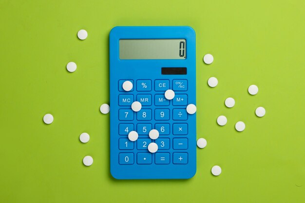 Calculation of the cost of medical expenses. Calculator and pills on green.