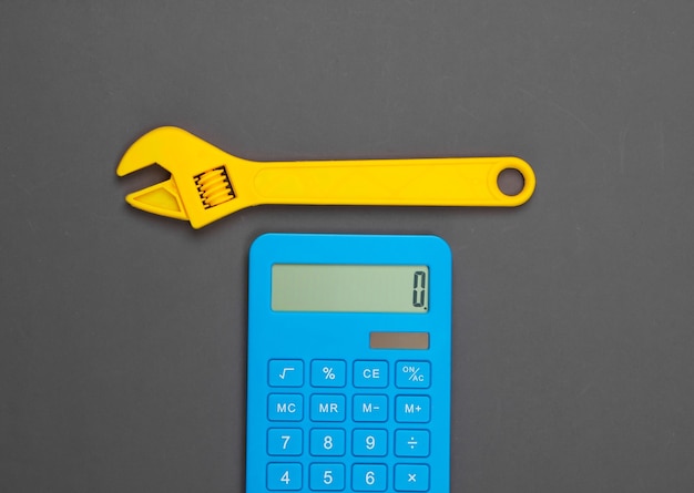 Calculation of the cost of repair work. Calculator and toy wrench on gray