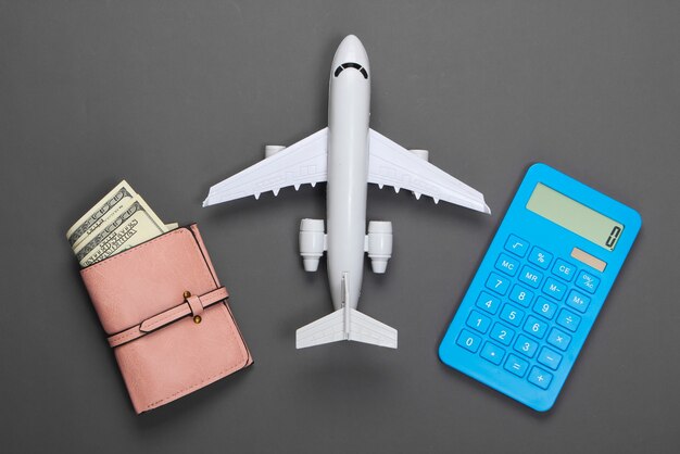 Calculation of the cost of tourism or resort. Flat lay. Figurine of passenger plane, calculator, wallet with wallet on gray.