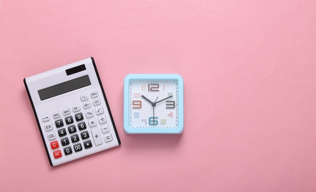 Calculator and alarm clock on a pink background Top view