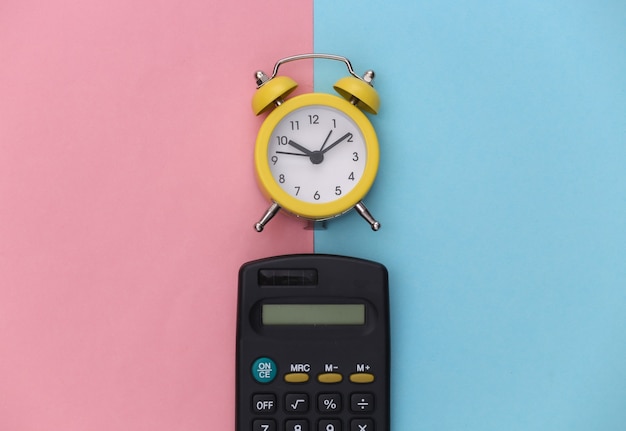 Calculator and alarm clock on pink blue pastel background.