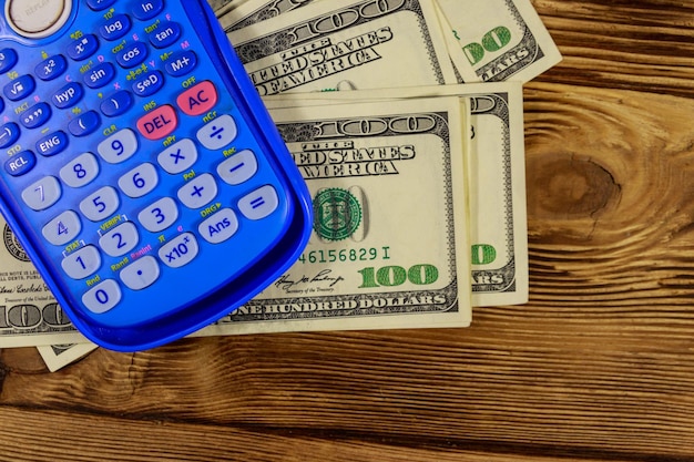 Calculator and american dollars banknotes on wooden table Top view