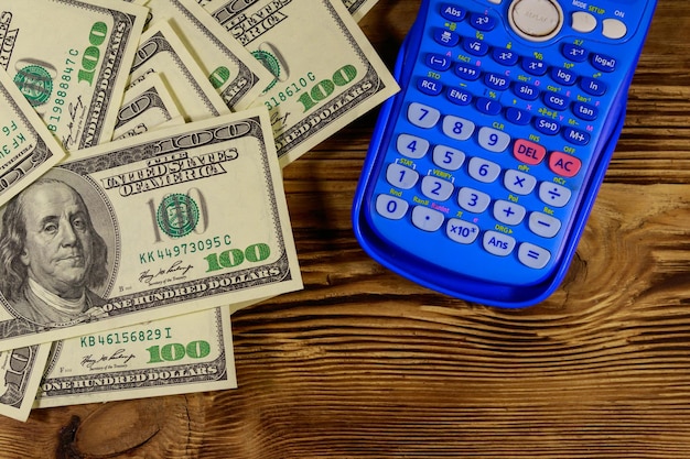 木製のテーブルの上の電卓と米ドル紙幣上面図