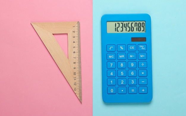 Фото Калькулятор и деревянная линейка, треугольник на голубой пастели. концепция образования
