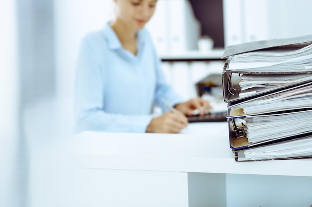 Calculator and binders with papers are waiting to be processed by business woman or bookkeeper back in blur. Internal Audit and tax concept.