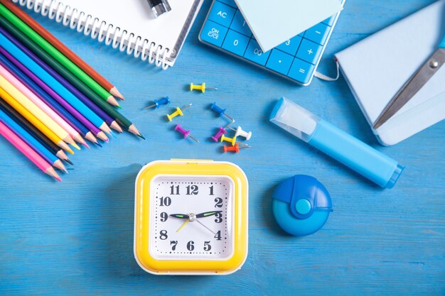 Calculator, clock, pencils, note, marker and sticky notes on the blue background