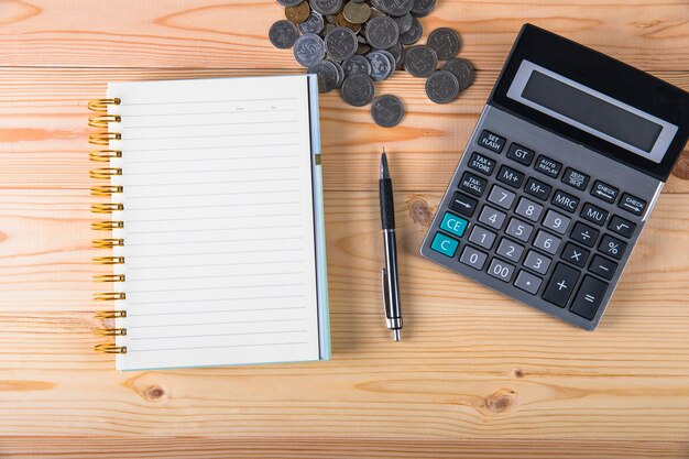 Calculator, coins, notepad and pen on the table