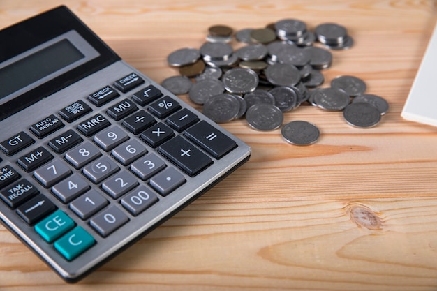 Calculator, coins, notepad and pen on the table