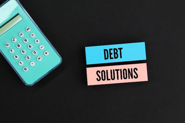 calculator and colored paper with the word Debt solutions debt settlement concept