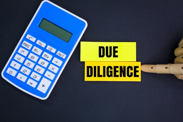 calculator and colored paper with the word due diligence business management concept