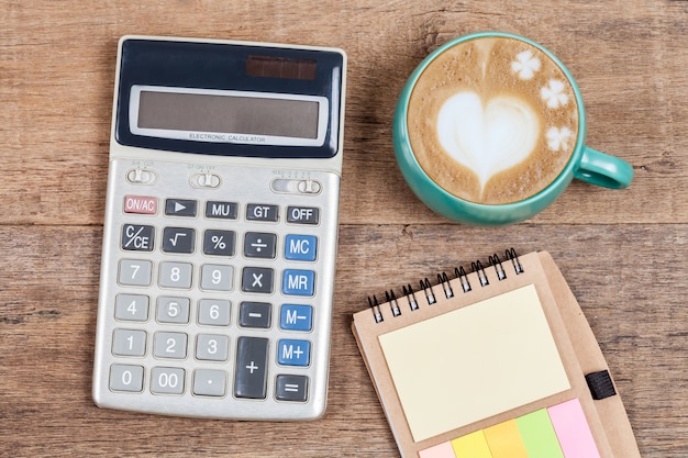 Calculator and cup of coffee on wood table.