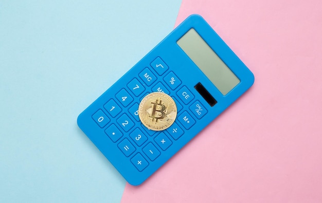 Calculator en bitcoin op blauw roze pastel achtergrond bovenaanzicht