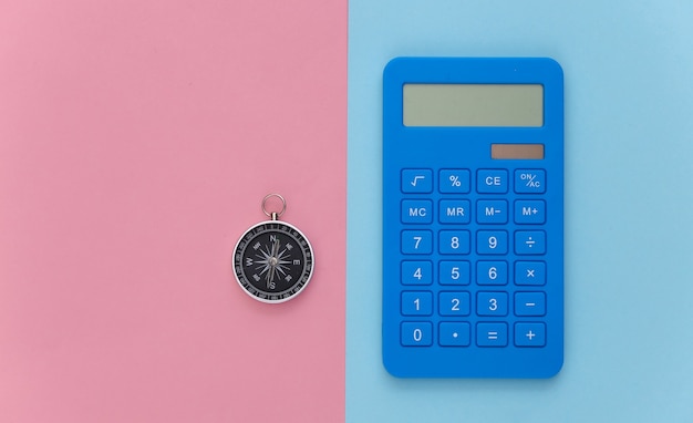 Calculator en kompas op een blauw-roze pastelachtergrond. Bedrijfsconcept. Bovenaanzicht