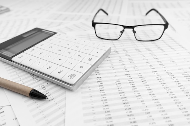 Calculator and eye glasses on financial statement Top view