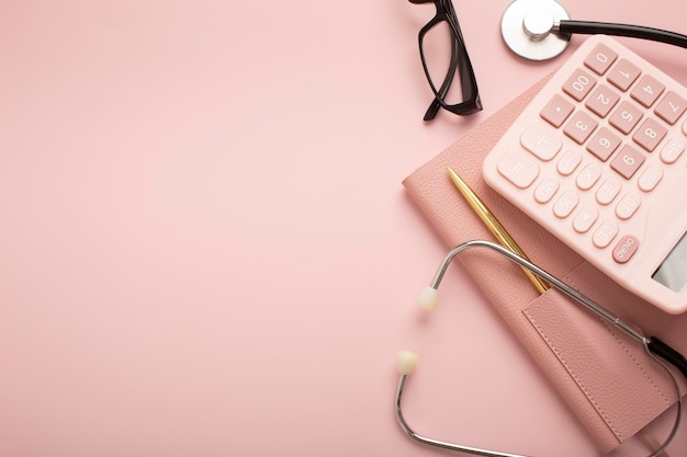 Calculator glasses notebook stethoscope on a pink background Place for text