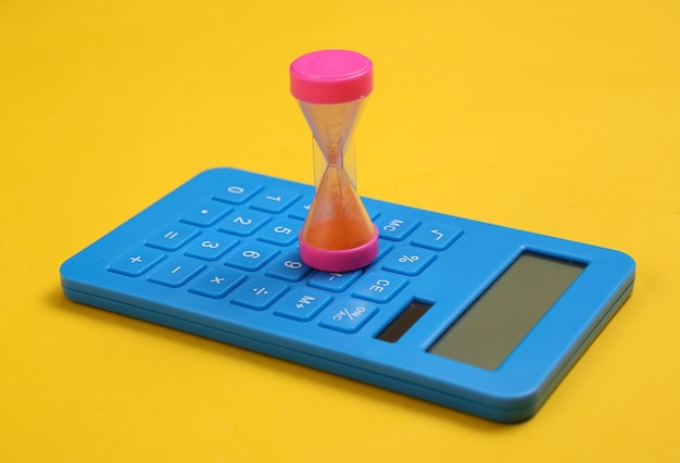 Calculator and hourglass on yellow background Income calculation investment deposit