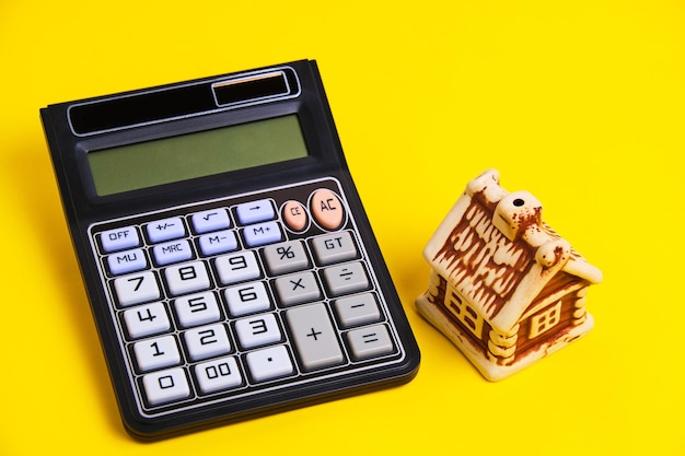 Calculator and house on a yellow background concept mortgage buying and selling housing