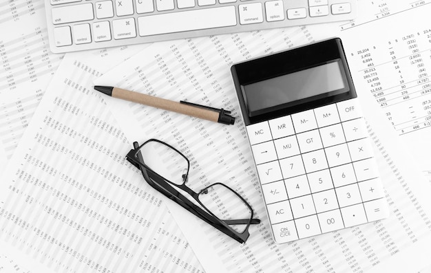 Calculator keyboard and eyeglasses lying on financial statement Financial concept