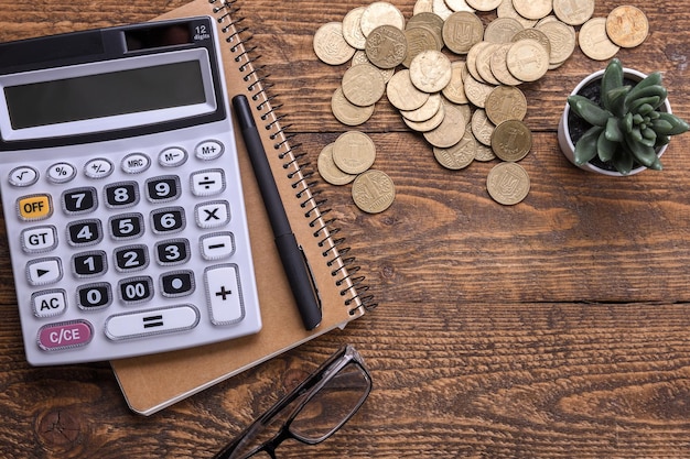 Calculator keypad,gold coins, pen and notebook on a wooden floor background. Top view. Copy space