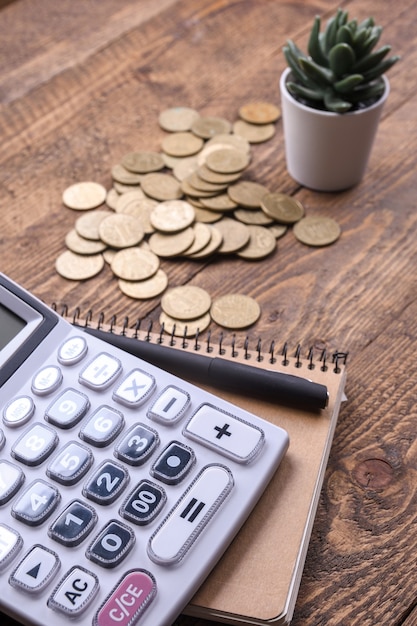 Calculator keypad,gold coins, pen and notebook on a wooden floor background