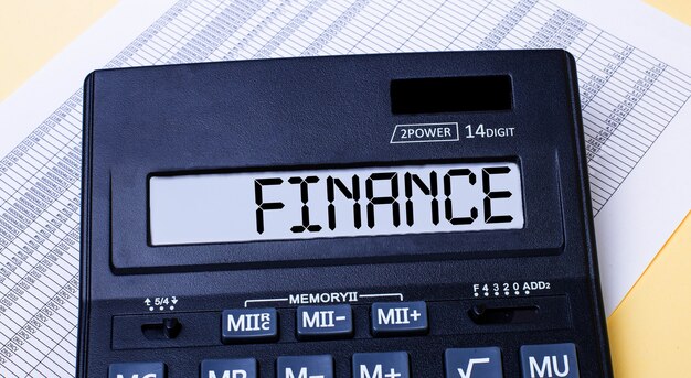 A calculator labeled FINANCE is on the table near the report. Financial concept.