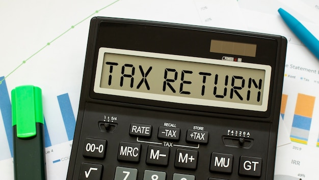 Photo a calculator labeled tax return lies on financial documents in the office